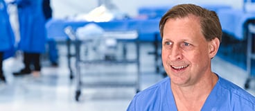 Dr. Stephen Quinnan, smiling in scrubs in an operating room like setting