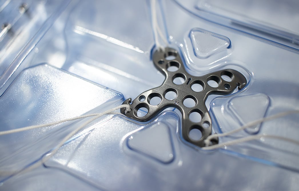 The Summit™ Patella Plate with attached sutures resting in the kit packaging