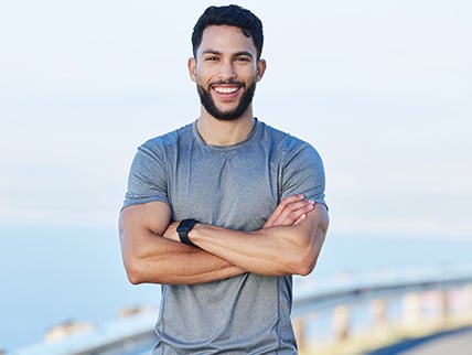 Man standing outdoors with his arms crossed, smiling