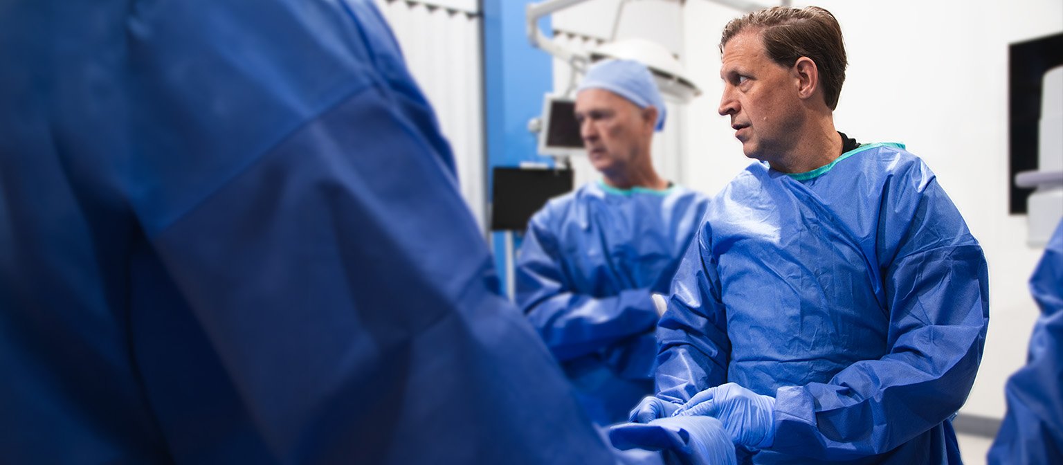 Surgical team in blue gowns working together in an operating room