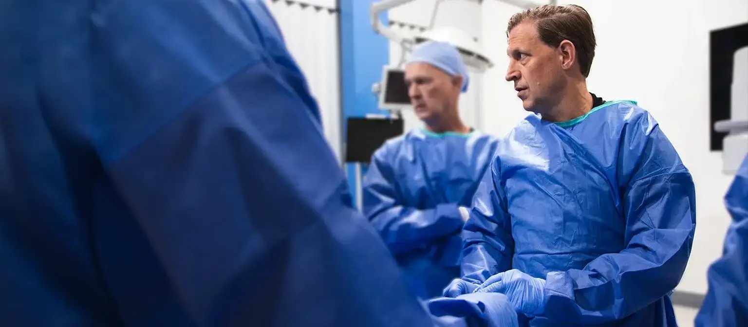 Surgical team in blue gowns working together in an operating room